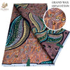 A roll of orange and brown African wax print fabric with swirling patterns, labeled as Grand Wax 100% Cotton.