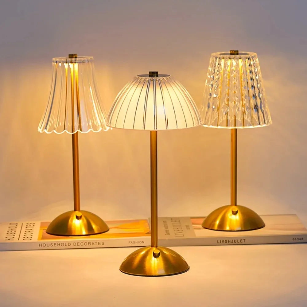 Three gold-toned crystal touch table lamps with translucent shades illuminate a surface.