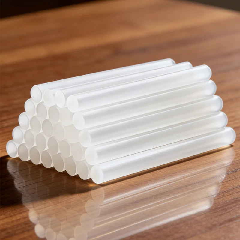 A row of clear, dual-size hot glue stick refills arranged in a neat rectangular shape on a wooden surface.