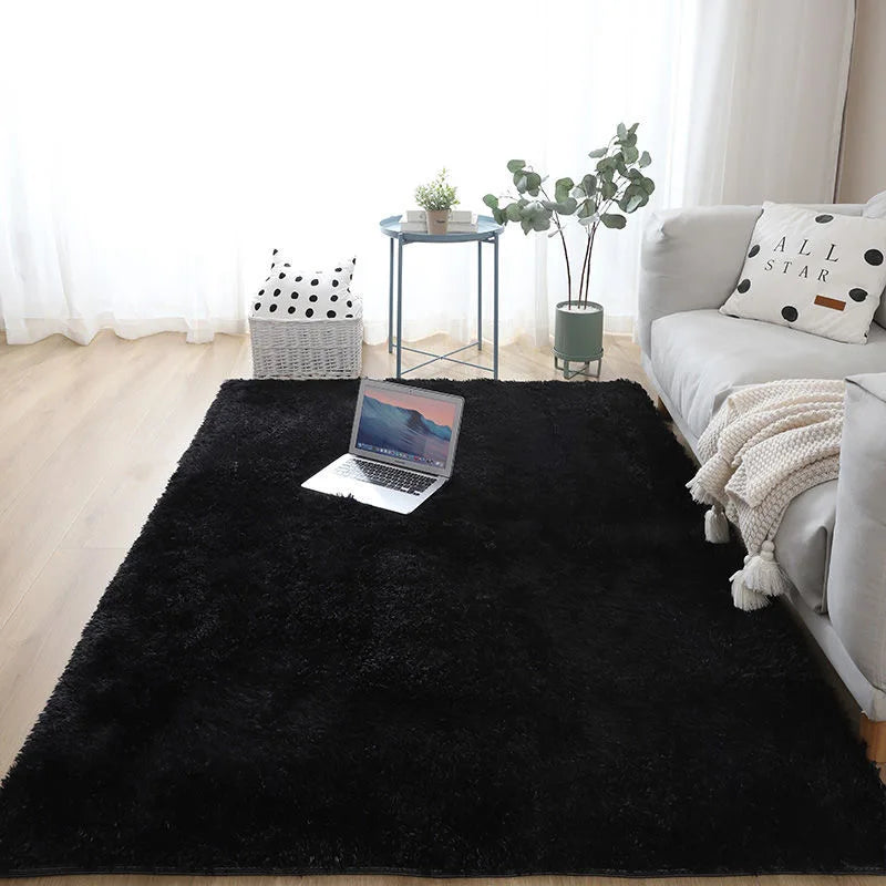 A black extra large Nordic fur rug placed on a light wood floor in a bright room with a sofa and plants.