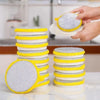A stack of yellow and white double-sided microfiber cleaning cloths for dishes, with a hand placing a cloth on a plate.