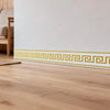A decorative yellow and white geometric border trim applied to a light wood floor.