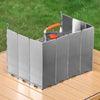Silver aluminum camping stove with an orange handle and windscreen resting on a wooden surface.