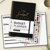A black spiral-bound budget planner with various sheets and stickers for monthly budgeting.