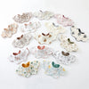 A collection of various patterned cotton baby feeding bibs in neutral tones and floral designs.