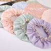 A collection of colorful reusable elastic shower caps in various pastel shades like pink, purple, and mint green.