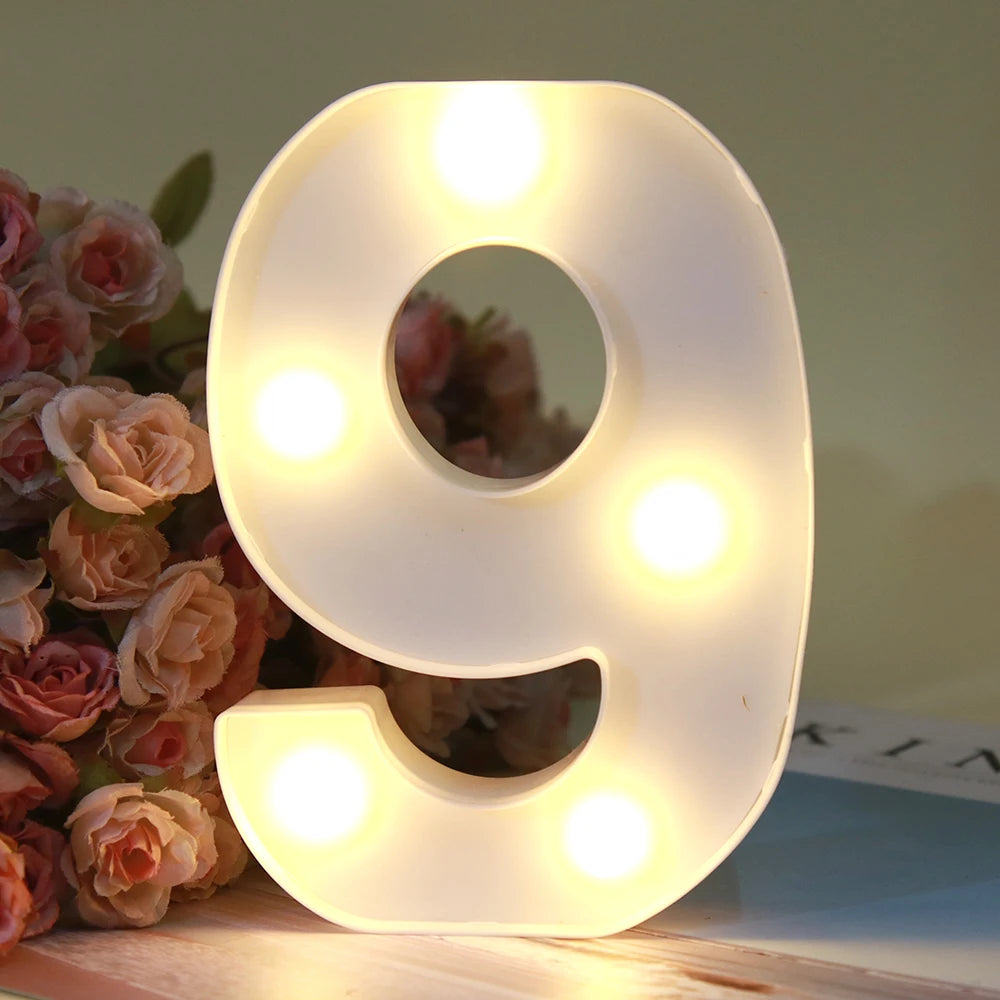 Lumière d'alphabet LED blanche en forme de chiffre 9, allumée et posée sur une surface en bois.