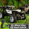 A black off-road RC vehicle with an alloy body and six wheels parked on green grass.