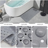 A gray non-slip suction cup bath mat with massage nodes shown next to a bathtub.