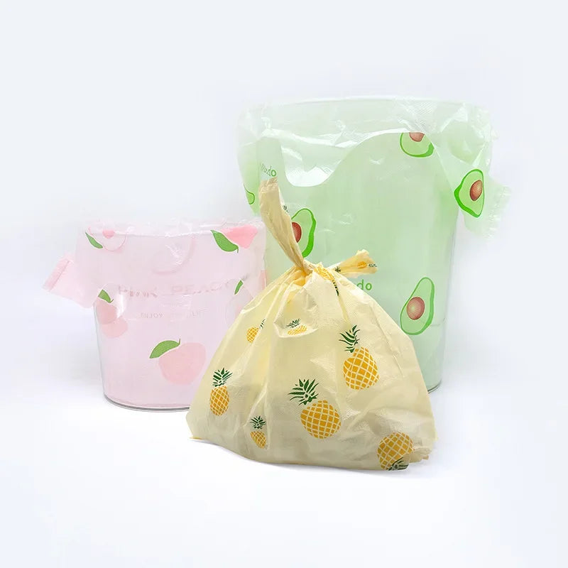 A set of mini fruit-print tote bags in pink and green are displayed against a white background.
