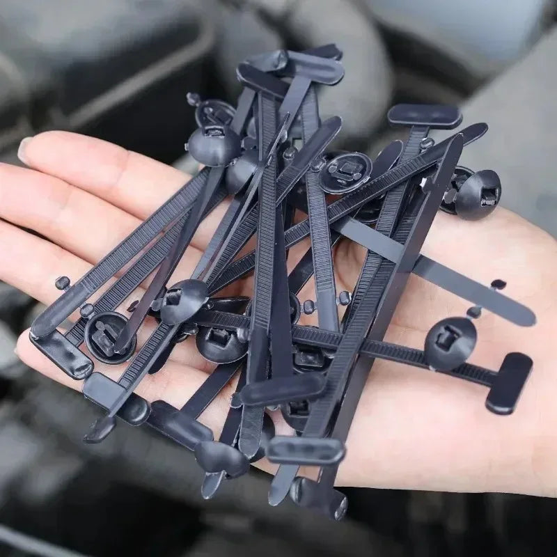 A hand holds several black self-locking nylon cable tie buckles for repairs.