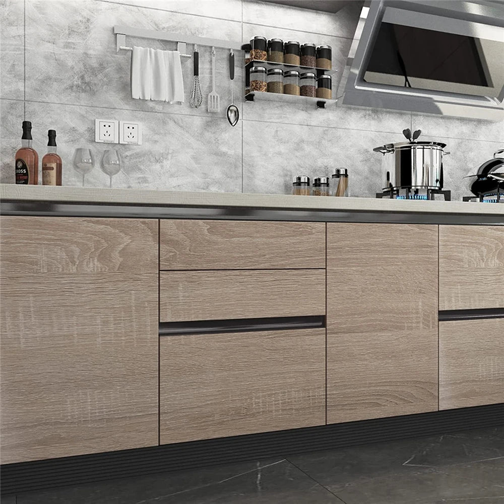 A modern kitchen featuring light wood grain cabinetry, stainless steel appliances, and a gray tiled backsplash.