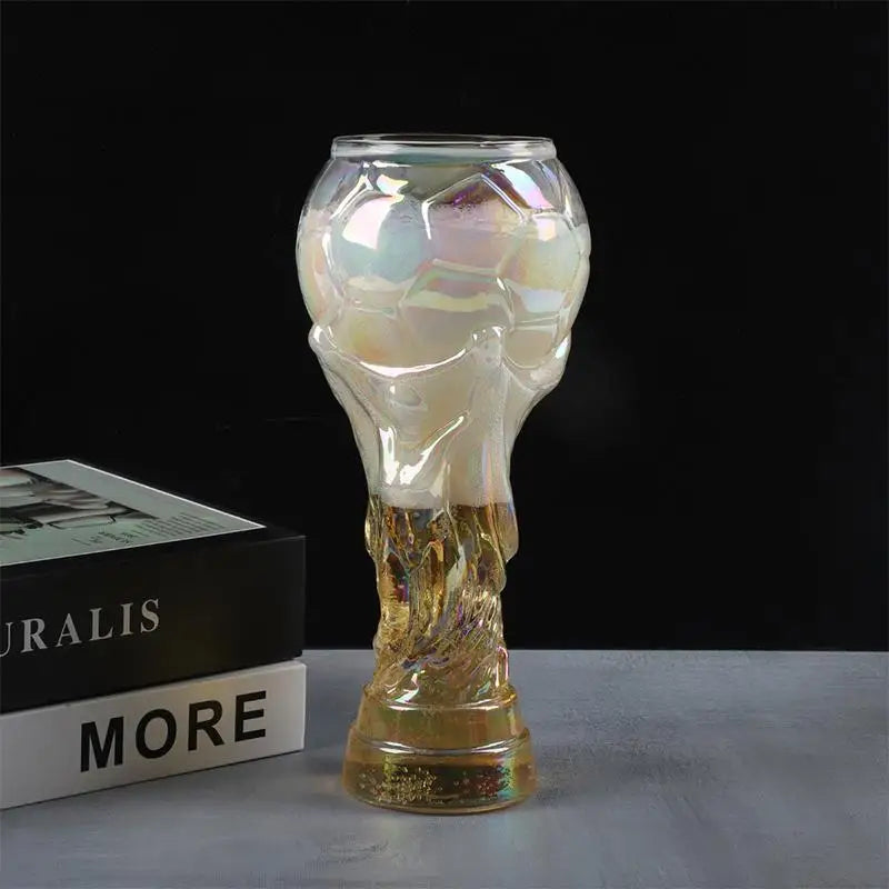 Trophäenförmiges Glasbierglas mit durchscheinender gelbgrüner, fleckiger Farbe auf grauem Untergrund.