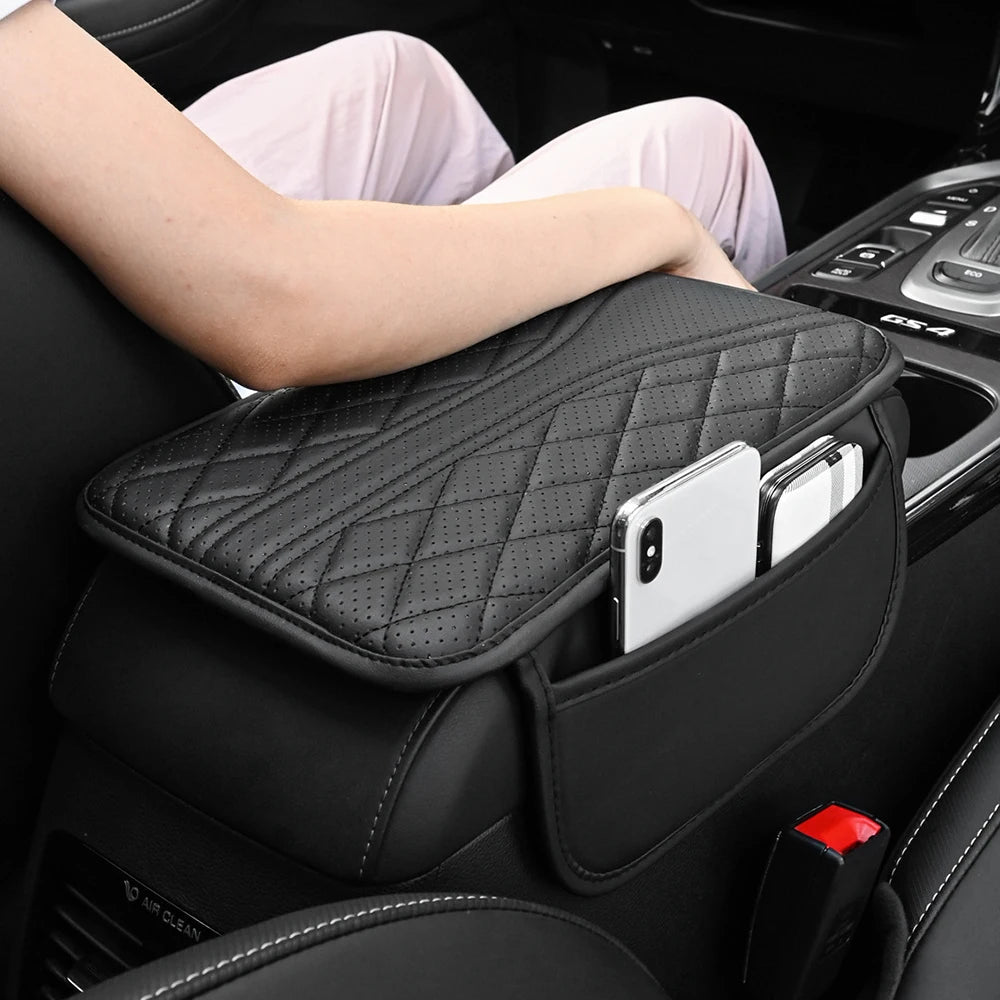 Eine schwarze Lederarmlehnen-Organizertasche wird im Autointerieur gezeigt, mit einer Hand, die darauf ruht.