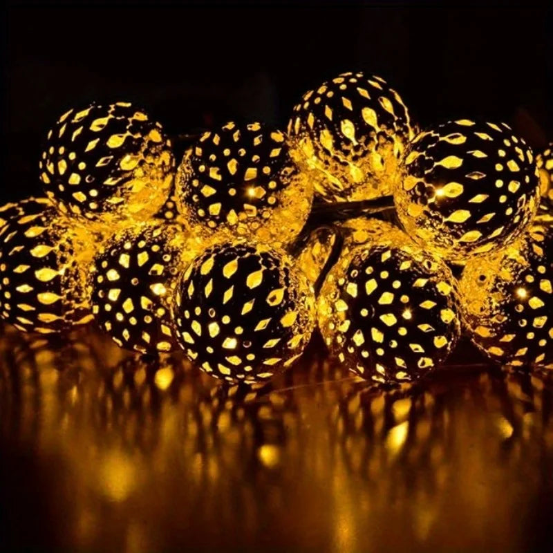 A close-up of glowing yellow Moroccan ball string lights reflecting on a dark surface.