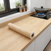 Roll of self-adhesive wood grain vinyl wallpaper contact paper displayed on a kitchen countertop.