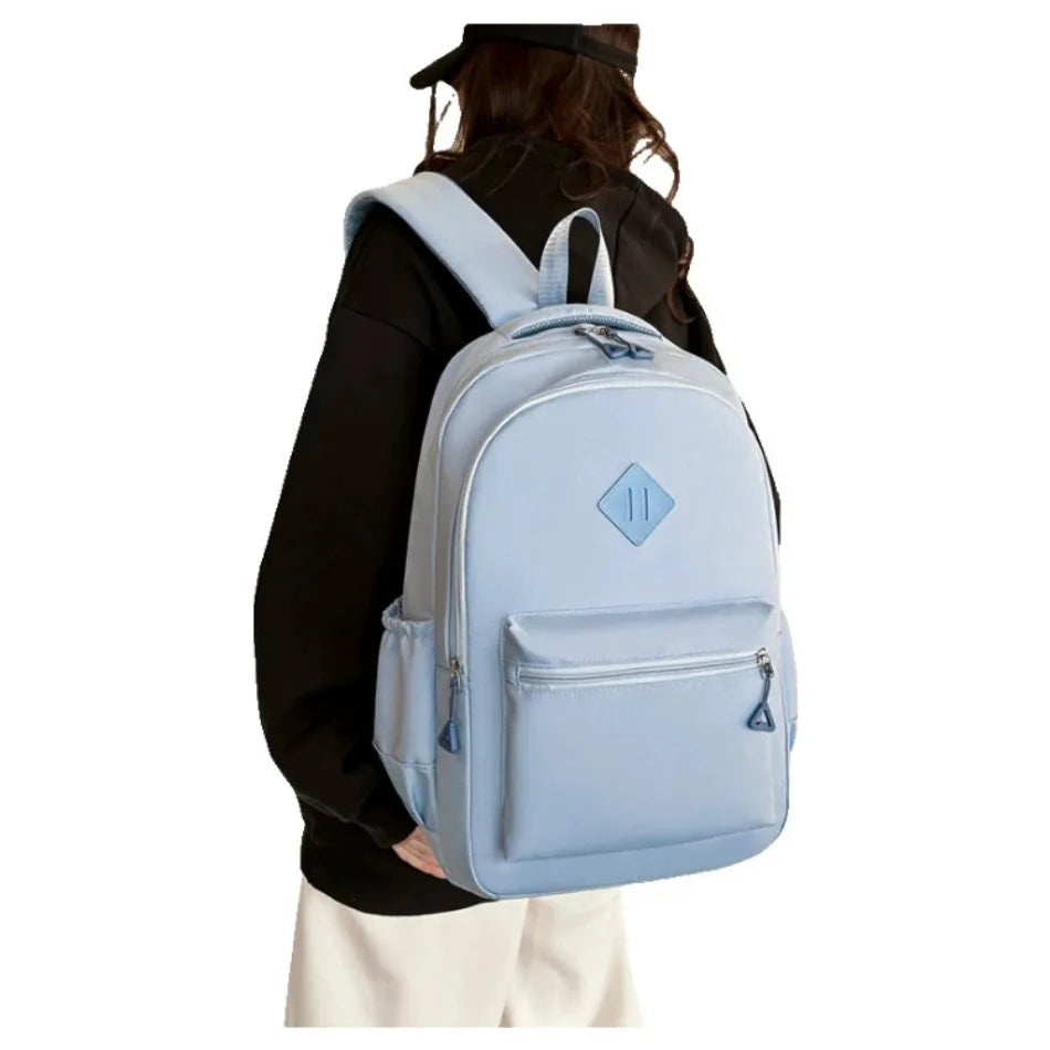 A light blue urban nylon backpack worn by a person, shown from the back.