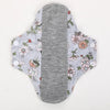 Reusable cotton menstrual pads featuring a light gray background with floral patterns and white buttons.