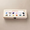 A wooden gift box containing twelve natural gemstone crystals arranged in labeled slots.