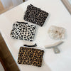 A collection of leopard print cosmetic bags and a clear silicone organizer on a white surface.