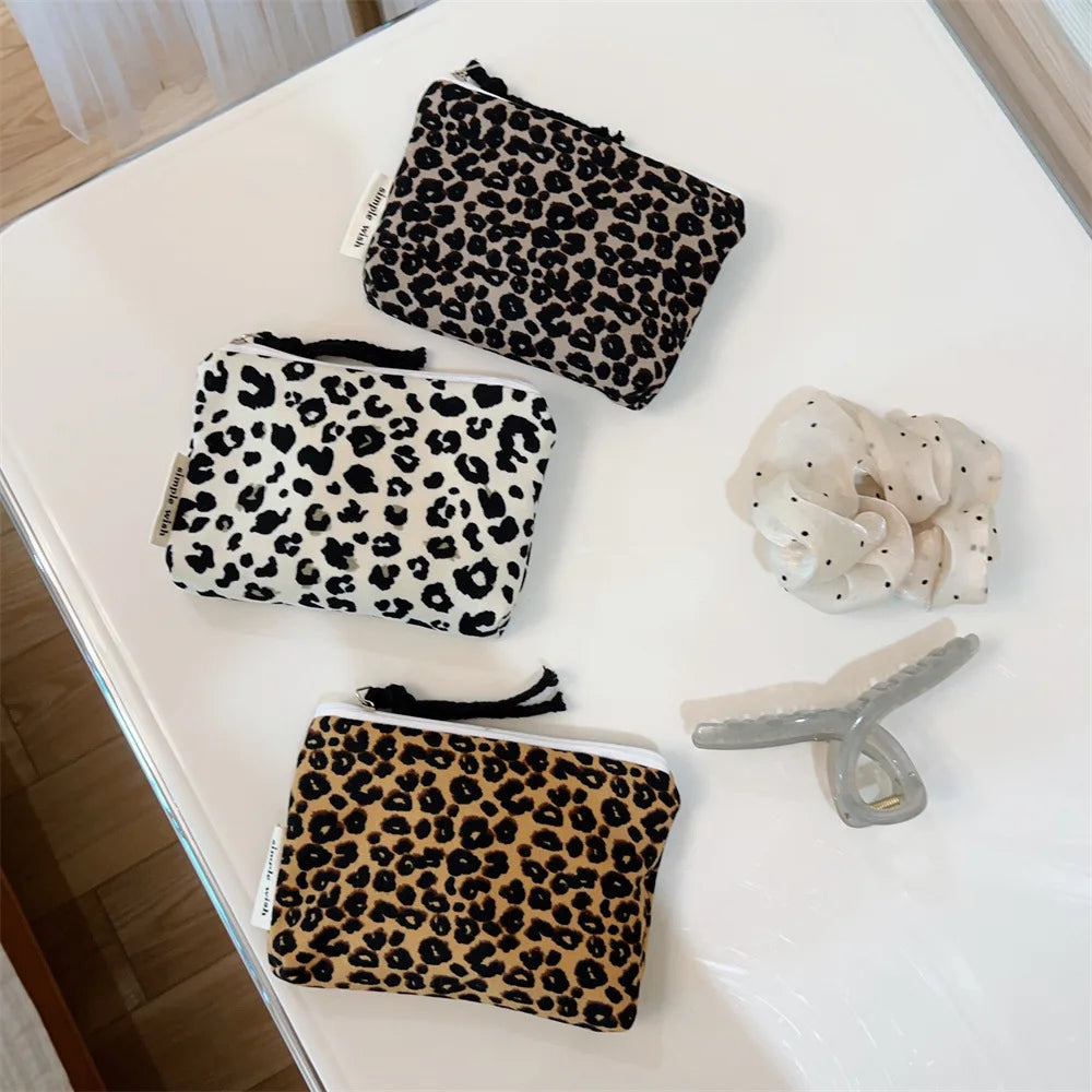 A collection of leopard print cosmetic bags and a clear silicone organizer on a white surface.