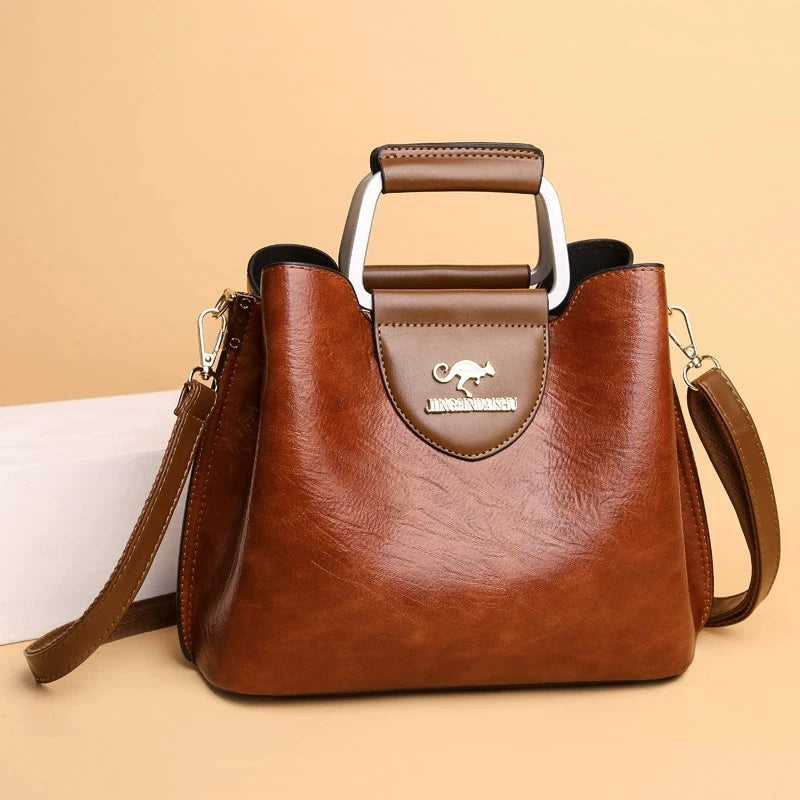 A brown leather vintage crossbody tote bag with a handle and multiple pockets is shown on a light background.