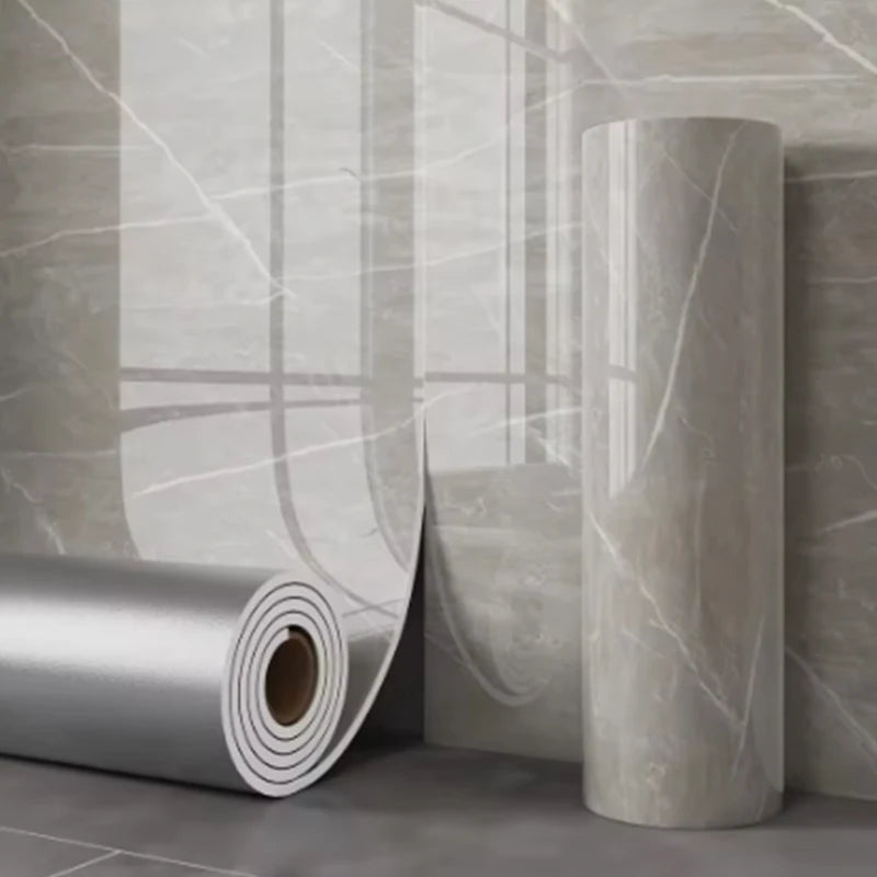 Roll of self-adhesive marble wallpaper showing a light gray veined pattern on a wall surface.