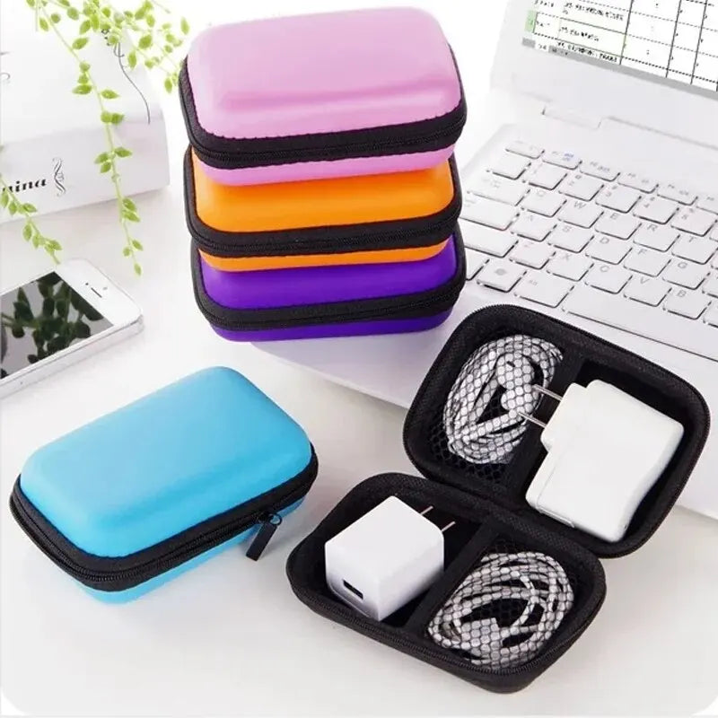A stack of colorful silicone pouches and an open black pouch displaying white cables on a white laptop surface.