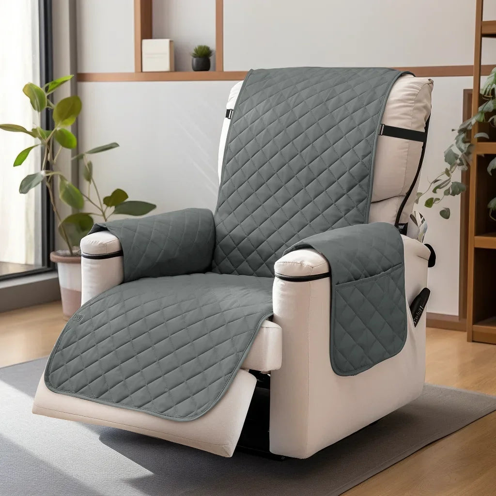 A gray quilted waterproof non-slip recliner sofa cover with side pockets resting on a floor.