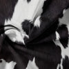 A close-up of a black and white cow print fabric draped in soft folds.