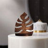 A rustic wooden wall-mounted storage rack shaped like a leaf, displayed on a white pedestal.