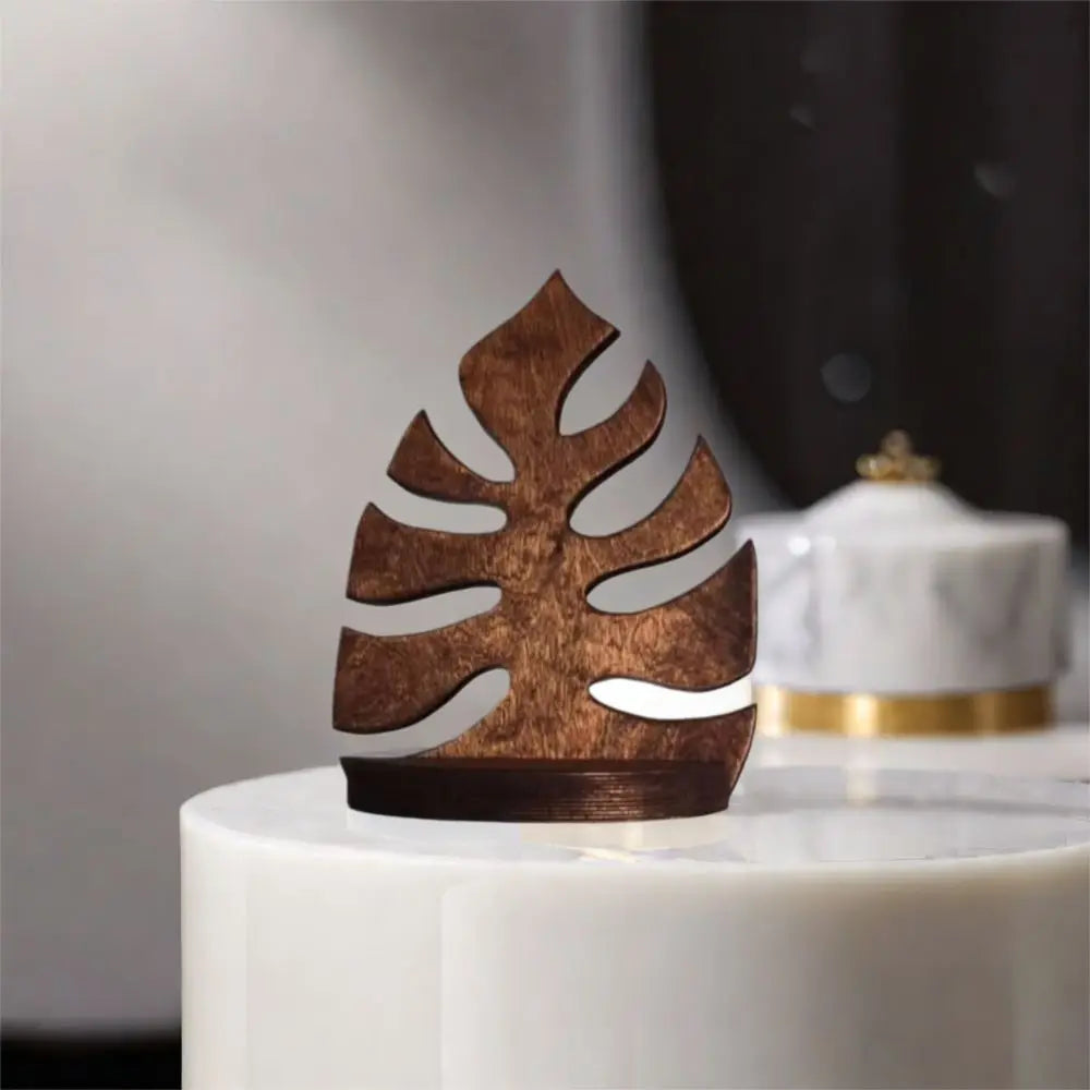 A rustic wooden wall-mounted storage rack shaped like a leaf, displayed on a white pedestal.