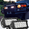 A close-up of four black LED flood light pods mounted on a truck grille and another pod lying separately.