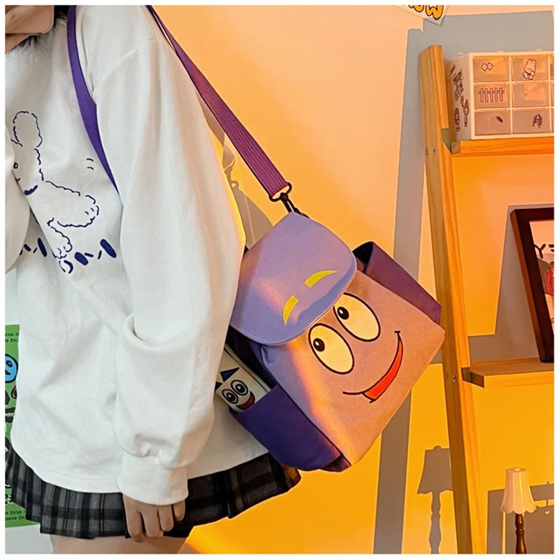 Eine Person hält einen lila und orange Flanellrucksack mit Dora The Explorer Figuren.