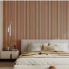 A bedroom featuring a wooden slat headboard wall panel and a bed with beige linens.