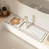 A white faucet mat with a flower design and a small wooden flower placed on it.