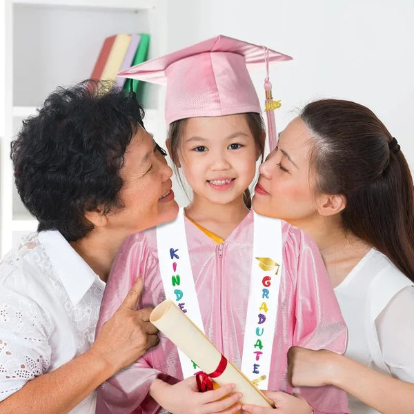 Drei Frauen feiern einen Kindergarten- und Vorschulabschluss mit einem jungen Mädchen in einem rosa Kleid