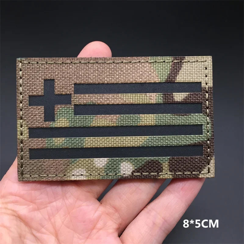 A close-up of a rectangular tactical patch featuring the American flag design in camouflage fabric.