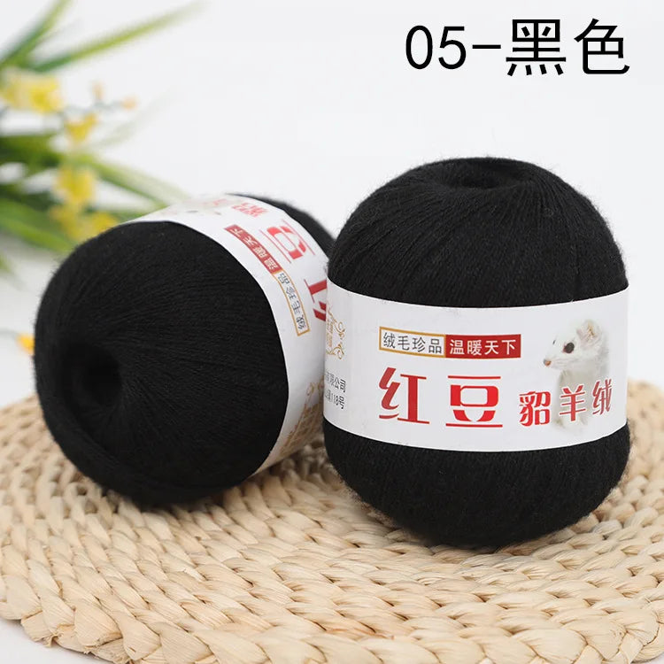 A ball of black yarn labeled 05-Black, displayed on a woven mat.