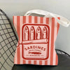 A pink and white striped canvas tote bag featuring a graphic print of sardines in olive oil.