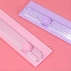 A pink portable paper cutter trimmer with a clear plastic blade is shown on a pink background.