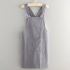 A gray linen kitchen apron hanging on a wooden hanger.