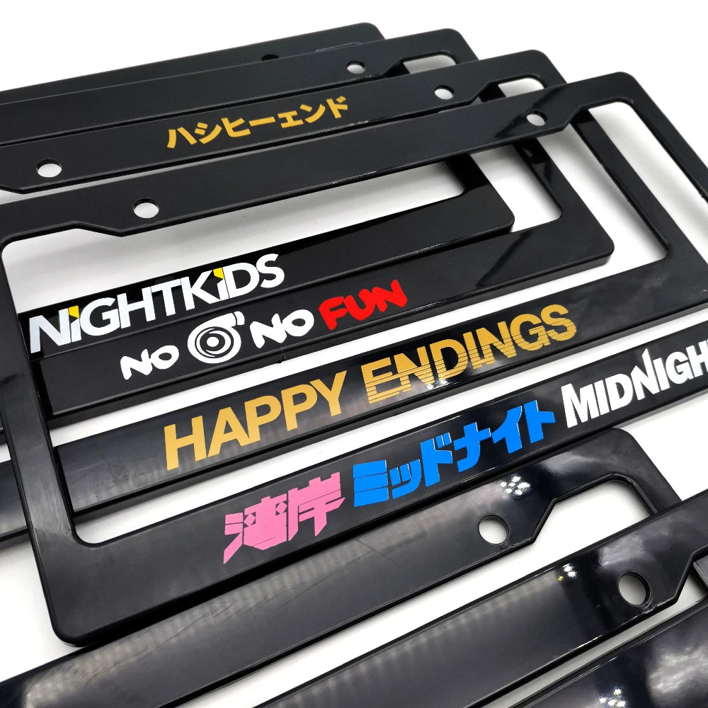 A pair of black racing style license plate frames featuring various text designs like HASHIEHAND and HAPPY ENDINGS