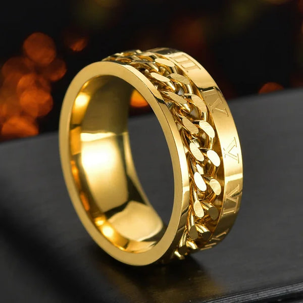 Anillo giratorio de acero inoxidable dorado con diseño de malla de cadena sobre una superficie oscura.