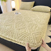 A beige plush mattress cover with an intricate diamond pattern is shown on a bed.