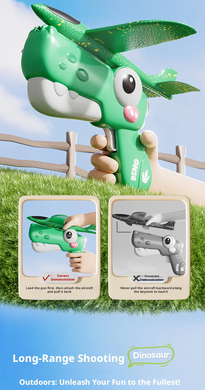 A hand holds a green dinosaur foam airplane launcher toy, demonstrating how to load and fire the toy.