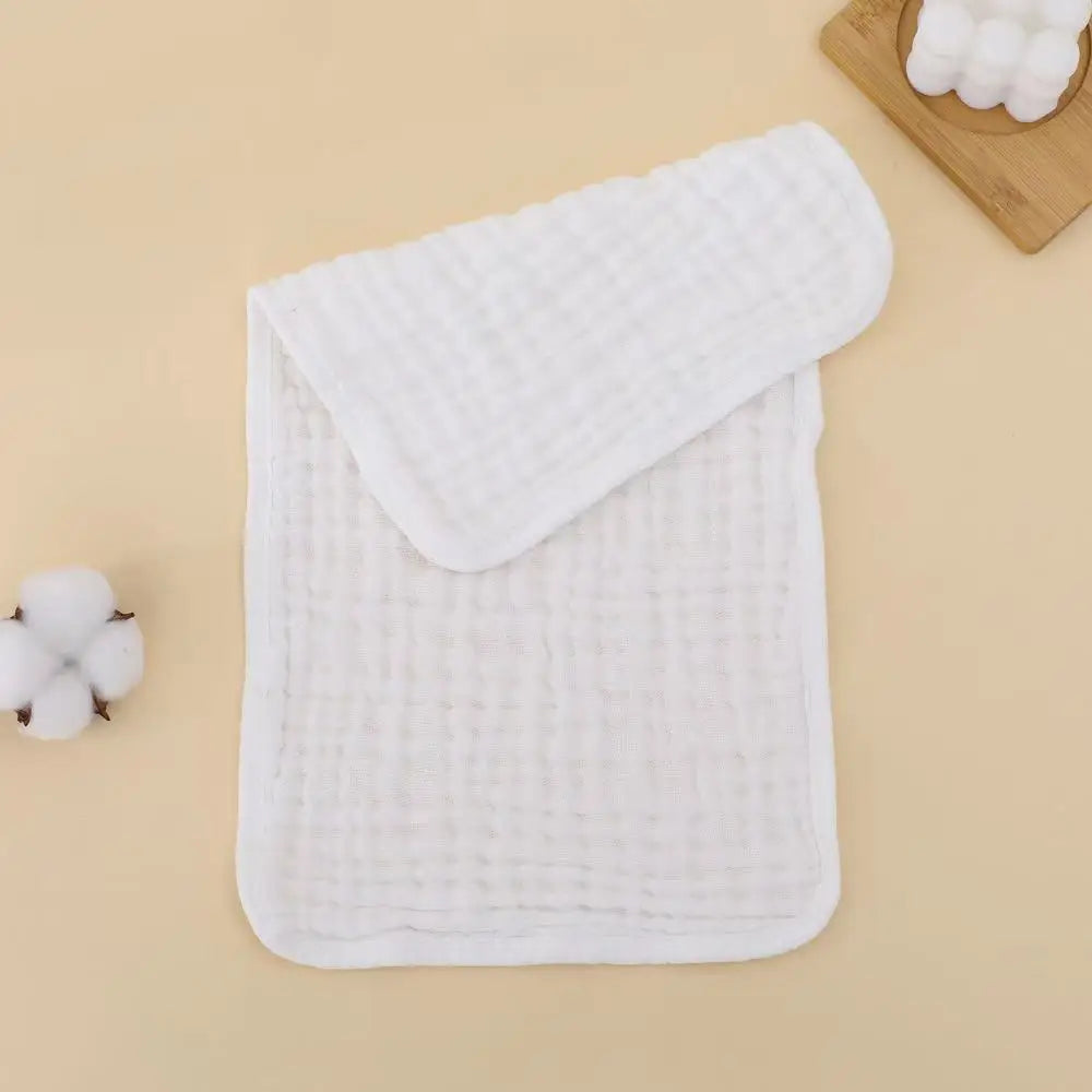 A stack of white, quilted muslin baby burp cloths is shown on a light background.