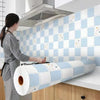 Roll of self-adhesive kitchen splashback sticker in white and light blue tiles mounted on a tiled wall.
