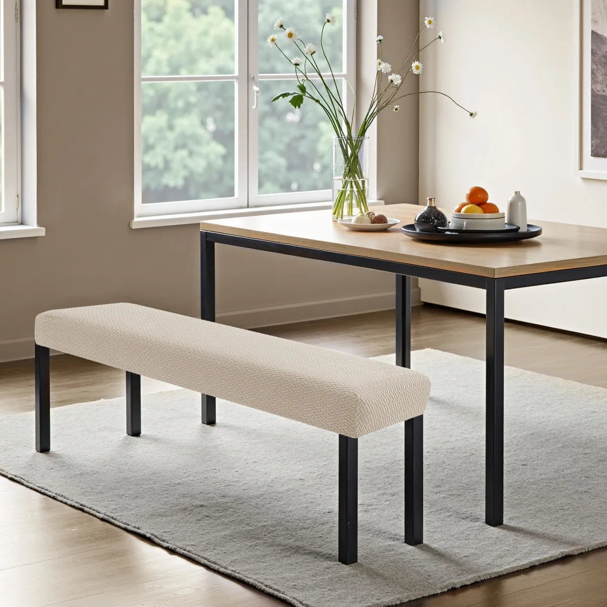 A light beige stretch jacquard bench cover placed on a modern wooden table in a bright room.