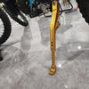 Close-up of a gold-colored CNC aluminum adjustable motorcycle kickstand for Sur Ron and Segway.